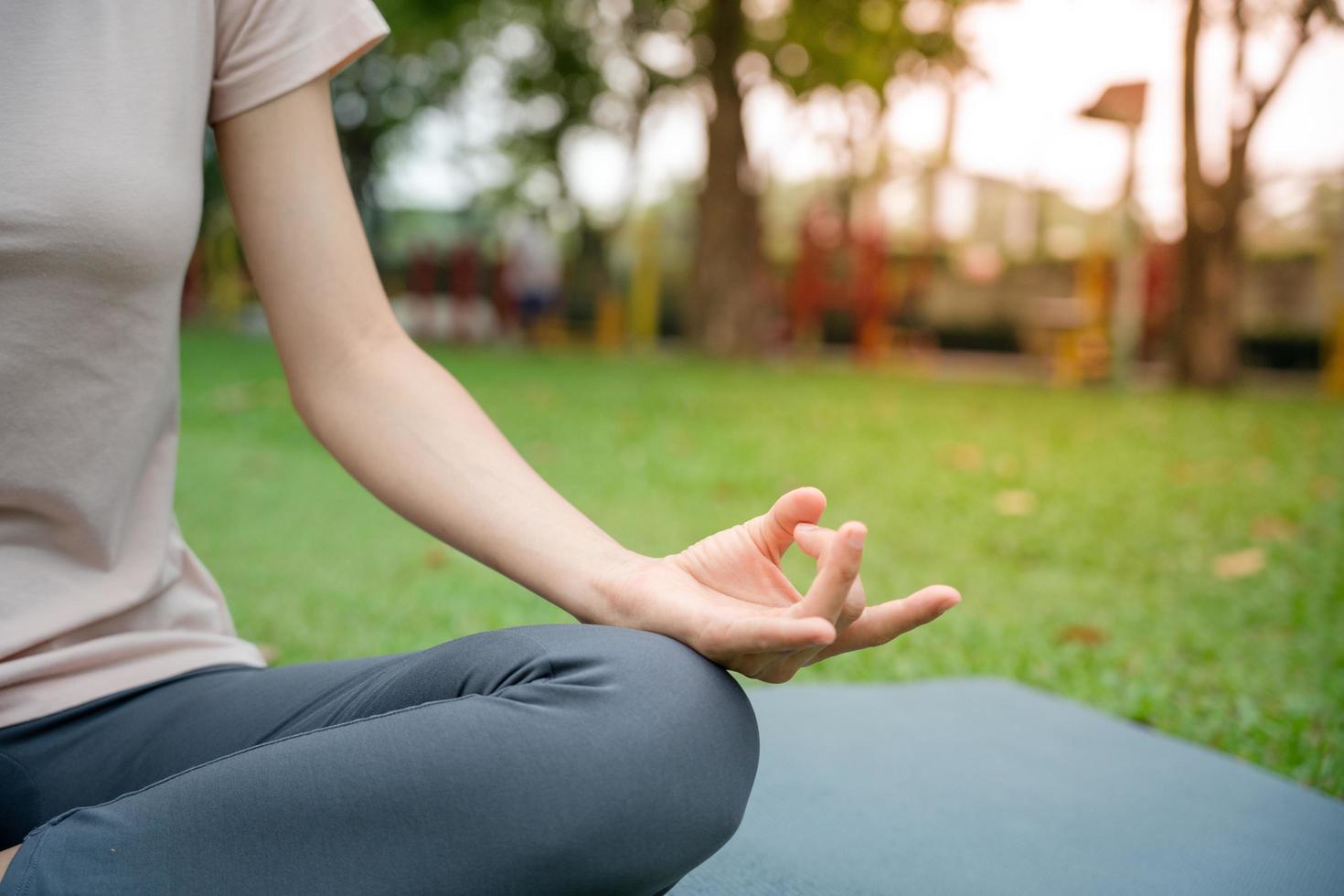 joven mujer delgada practicando yoga en el parque. chica haciendo ejercicios en la mañana. equilibrio, meditación, relajación, concepto de estilo de vida saludable foto