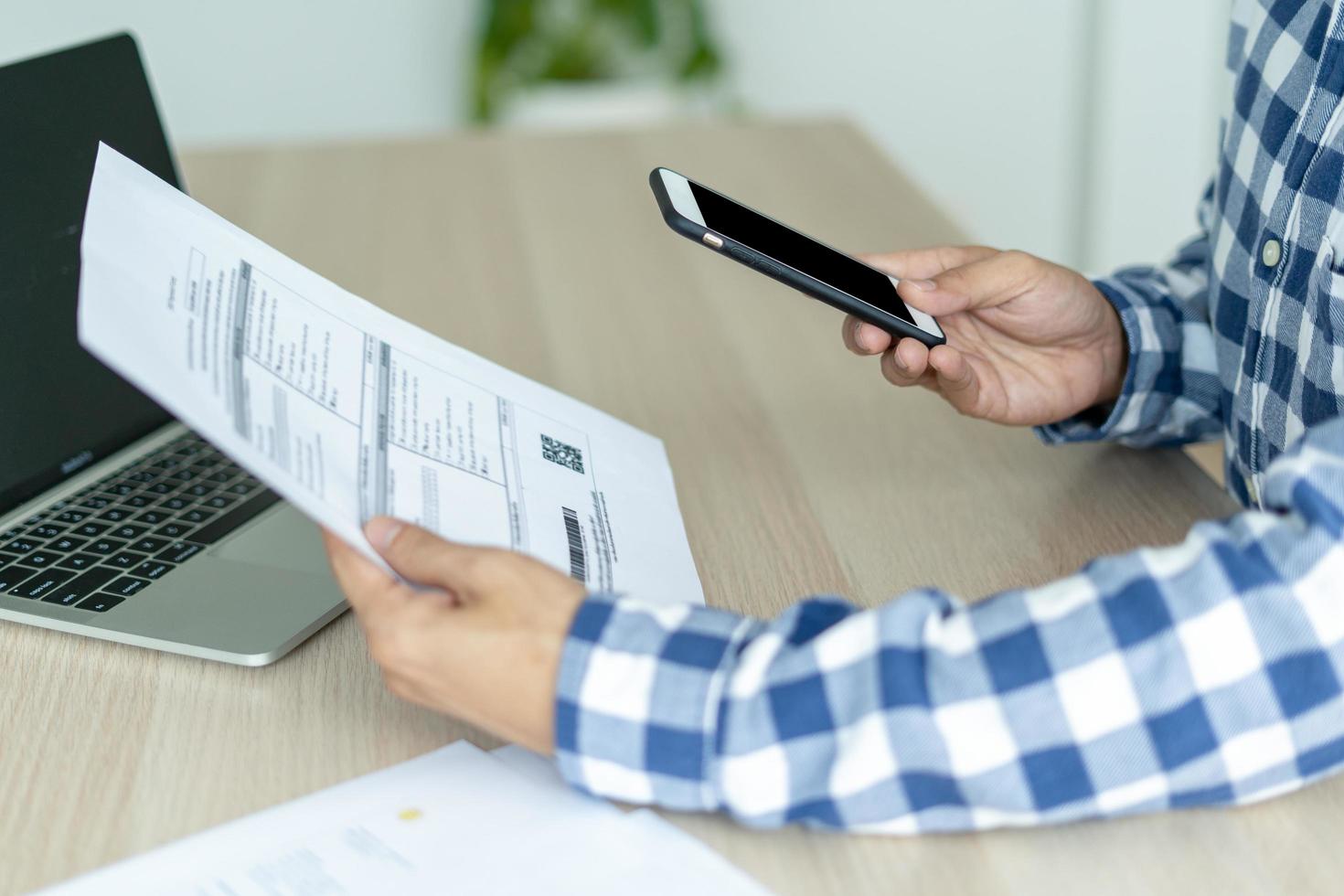 business man use phone to scan barcode or QR codes to pay credit card bill after receiving document invoice online. payment, receive, paying electricity, digital payments without money, technology photo