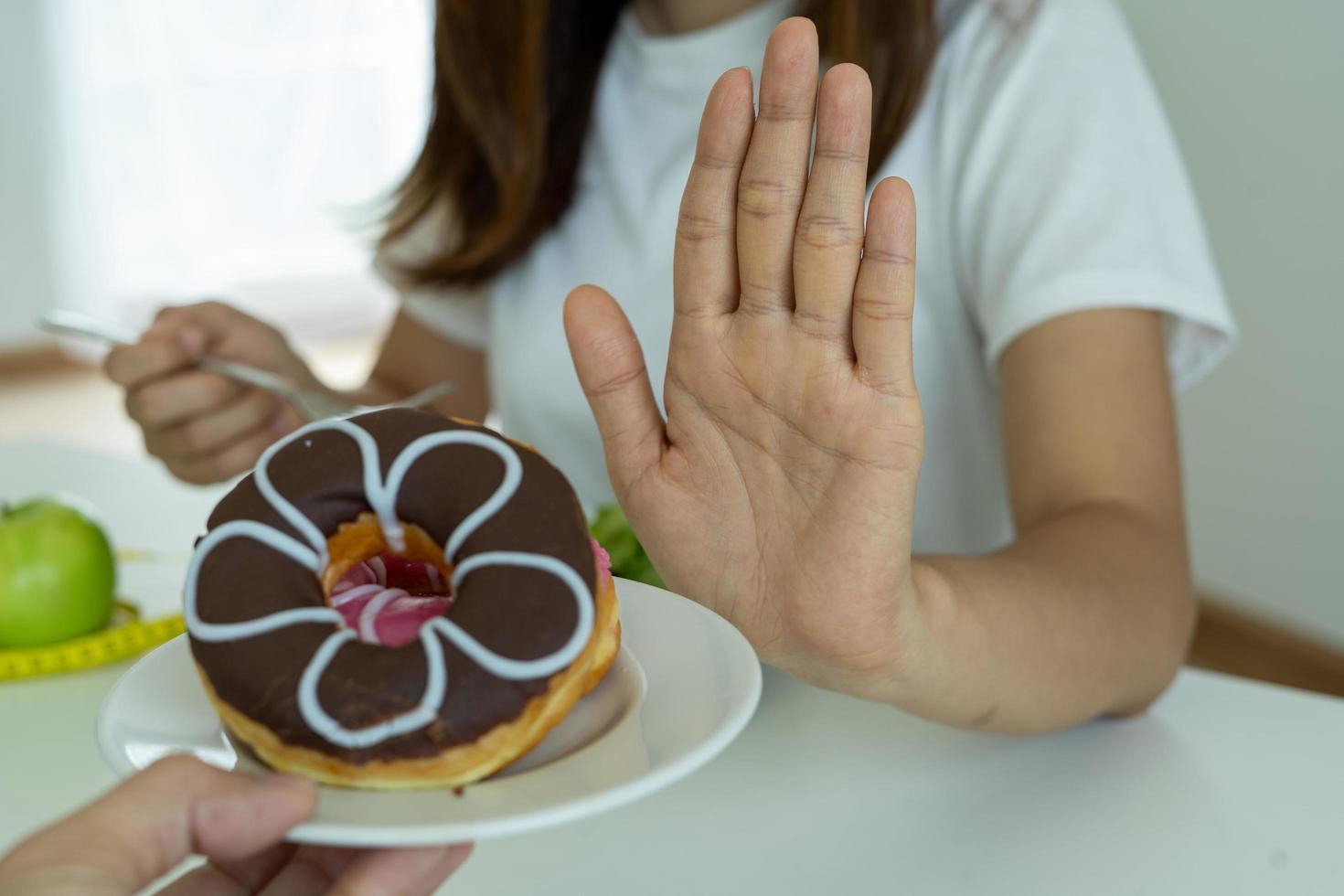 Women reject junk food or unhealthy foods such as doughnuts and choose healthy foods such as green apples and salads. Concept of fasting and good health. photo