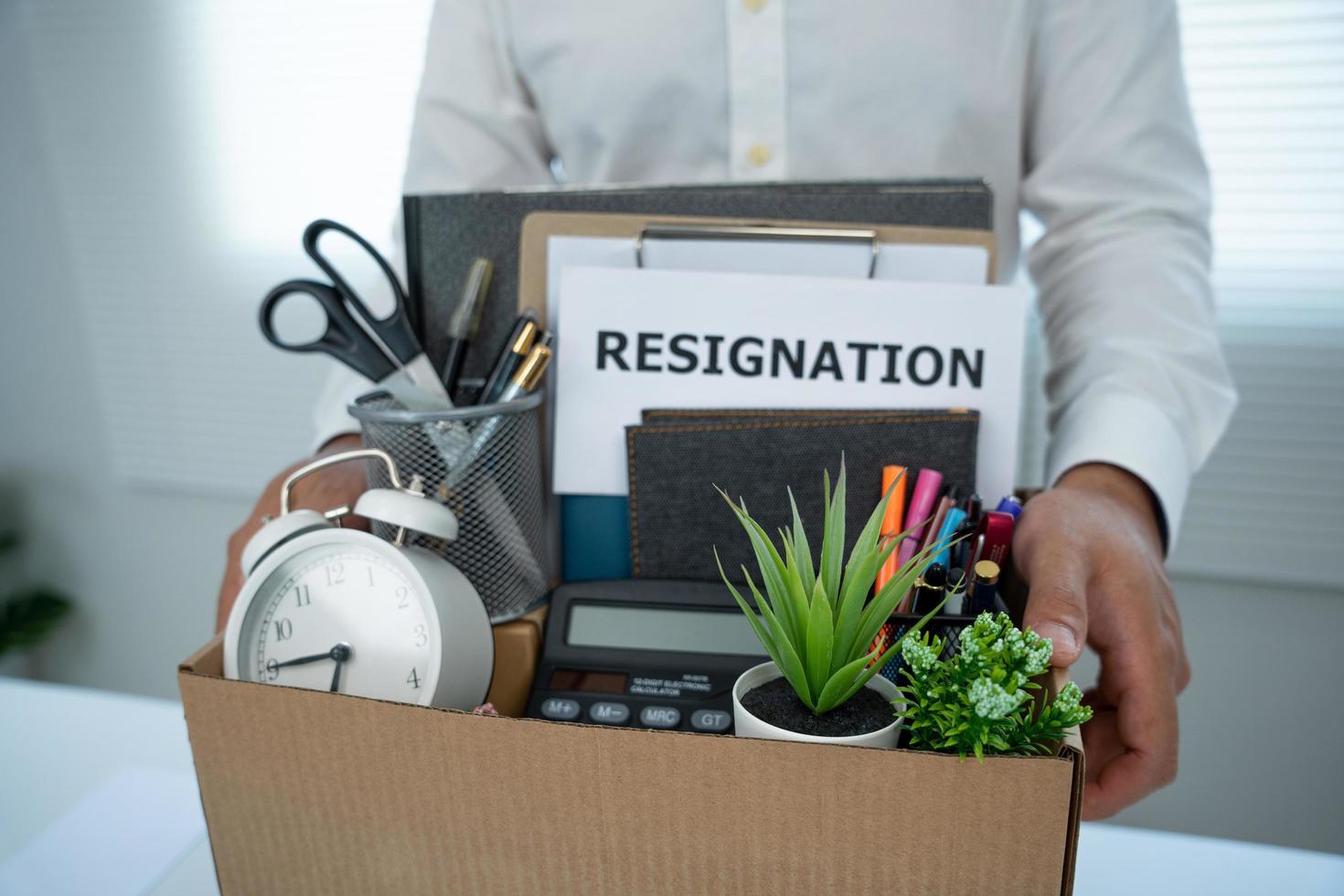 joven empresario pone pertenencias personales en una caja después de enviar una carta de renuncia. empleados fueron despedidos de sus trabajos. cambiar de posición y mover funciones. foto