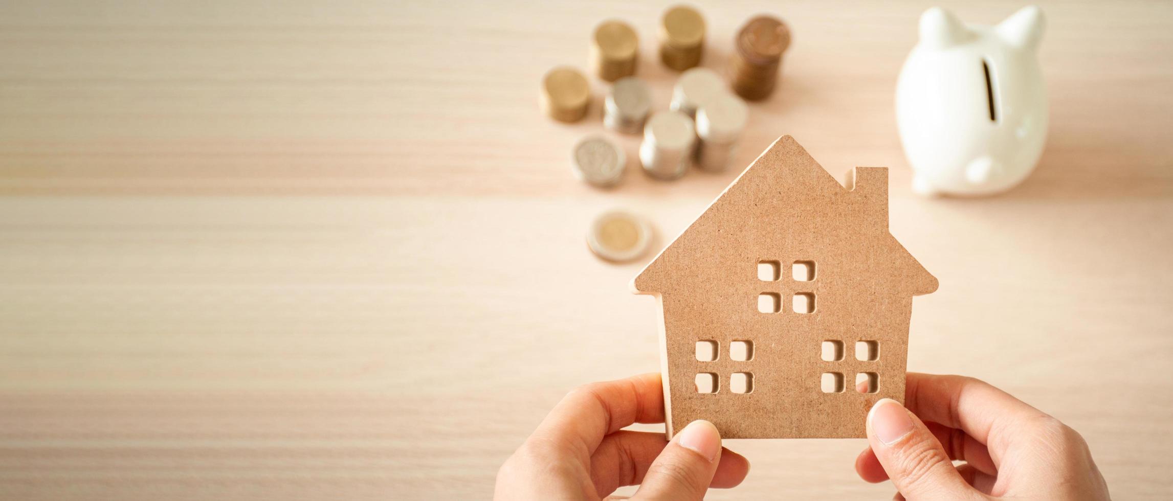 A house held on the hands of a woman planning to save money to invest in real estate. For saving or investing for a home. photo