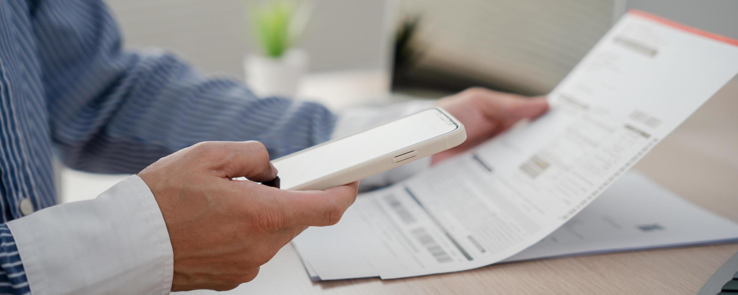 business man use phone to scan barcode or QR codes to pay credit card bill after receiving document invoice online. payment, receive, paying electricity, digital payments without money, technology photo