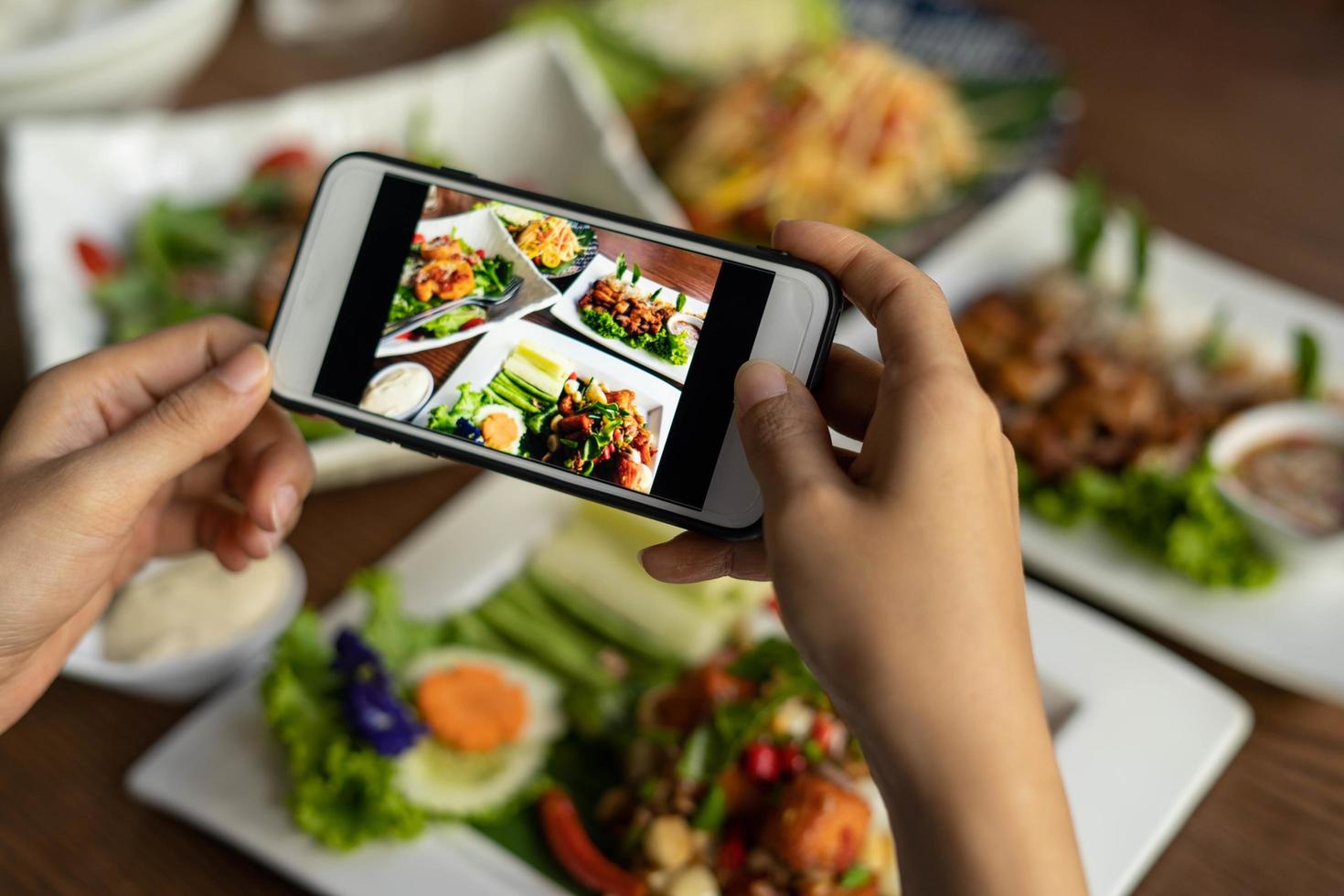 Woman take picture of a meal on the table after ordering food online to eat at home. Photography and use phone concepts photo