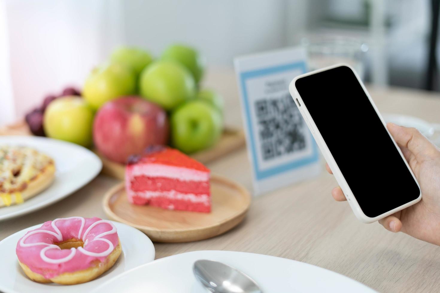 la mujer usa un teléfono inteligente para escanear el código qr para pagar en un café restaurante con un pago digital sin efectivo. elige menú y ordena acumula descuento. billetera electrónica, tecnología, pago en línea, tarjeta de crédito, aplicación bancaria foto