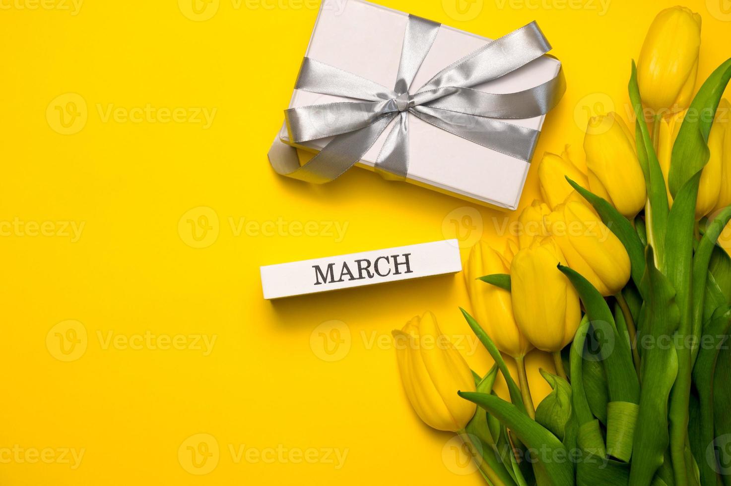 Spring banner. A bunch of yellow tulips and march written on a wooden block. Women's day concept photo