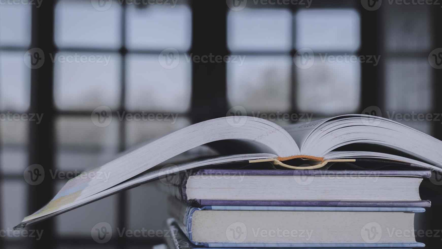 pila o capa de libros antiguos antiguos sobre una mesa de madera. concepto de aprendizaje, educación y estudio. uno de ellos abierto con espacio de copia. foto