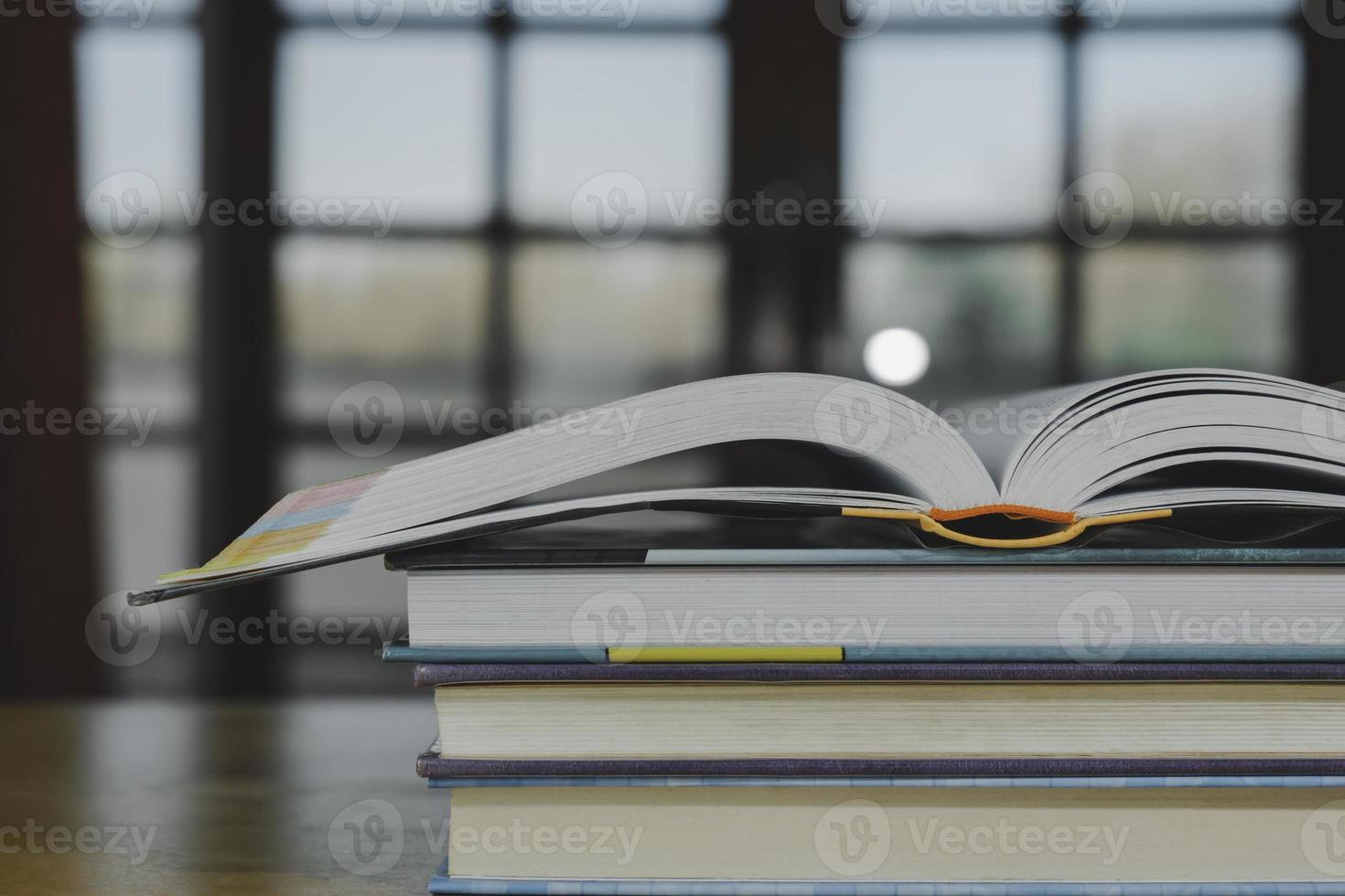 Stack or plie of vintage old books on wooden table. Learning, education and study concept. one of them open with copy space. photo