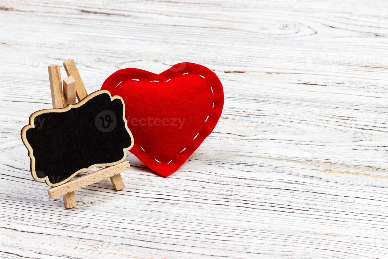 Red heart and small blackboard with copy space on a black background. Valentine's day composition photo