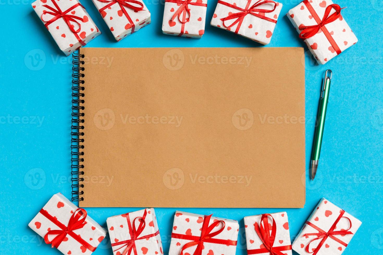 Top view of craft notebook surrounded with gift boxes on colorful background. Valentine's day photo
