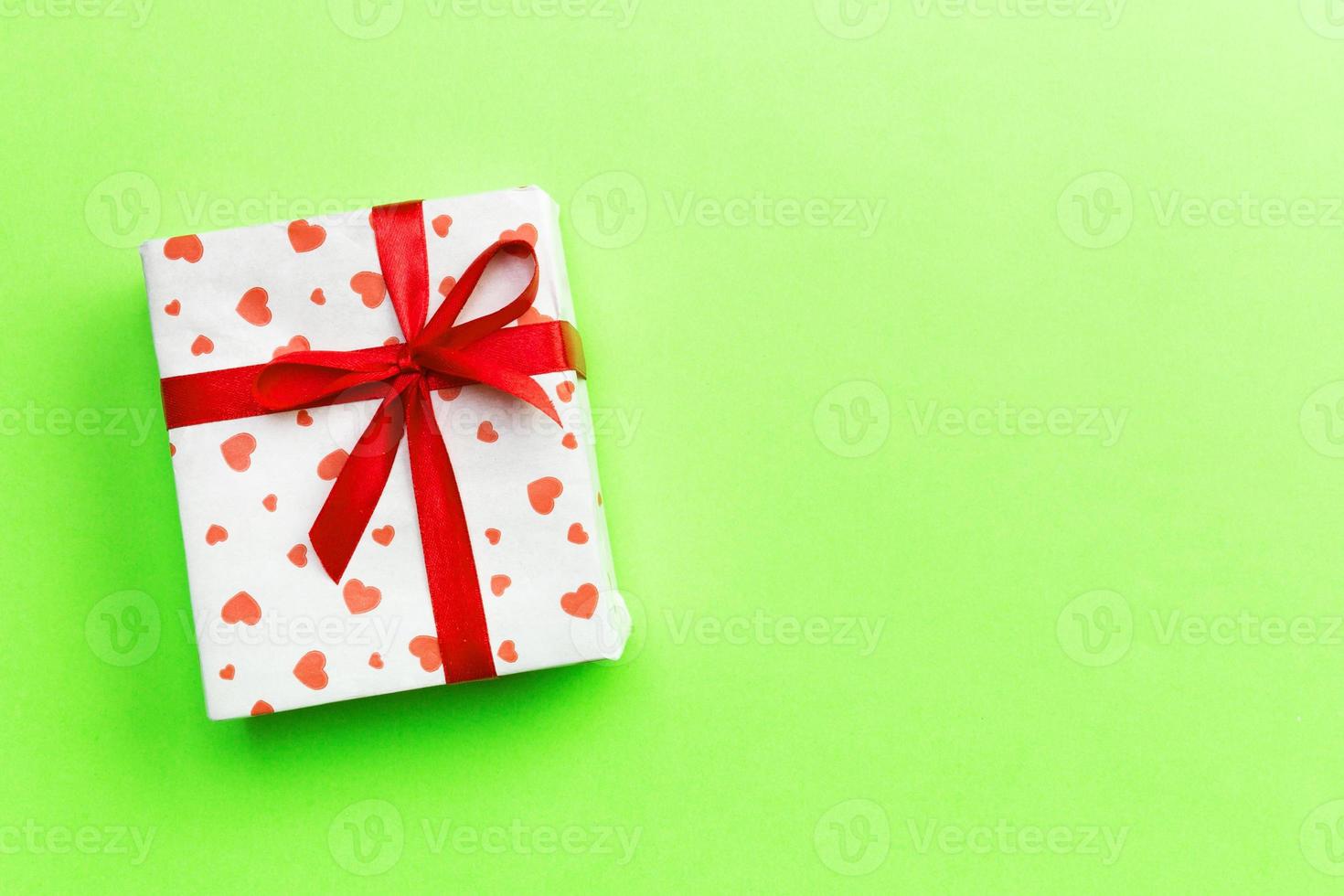Background with gift box and hearts on green Background. Top view with copy space for text photo