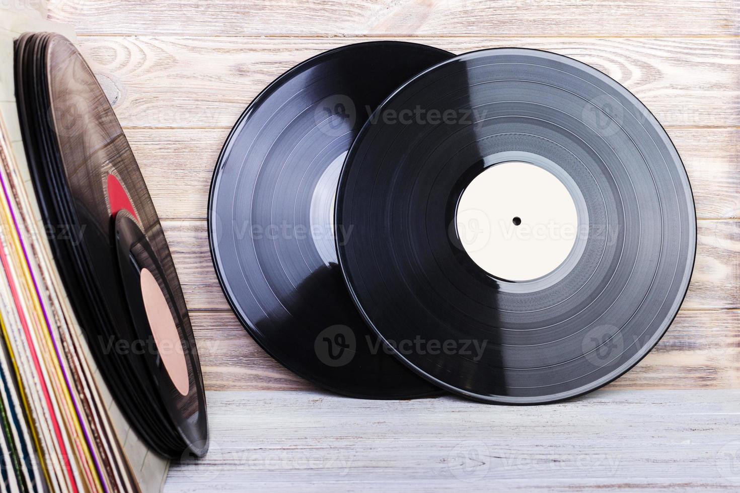 Retro styled image of a collection of old vinyl record lp's with sleeves on a wooden background. Copy space. photo