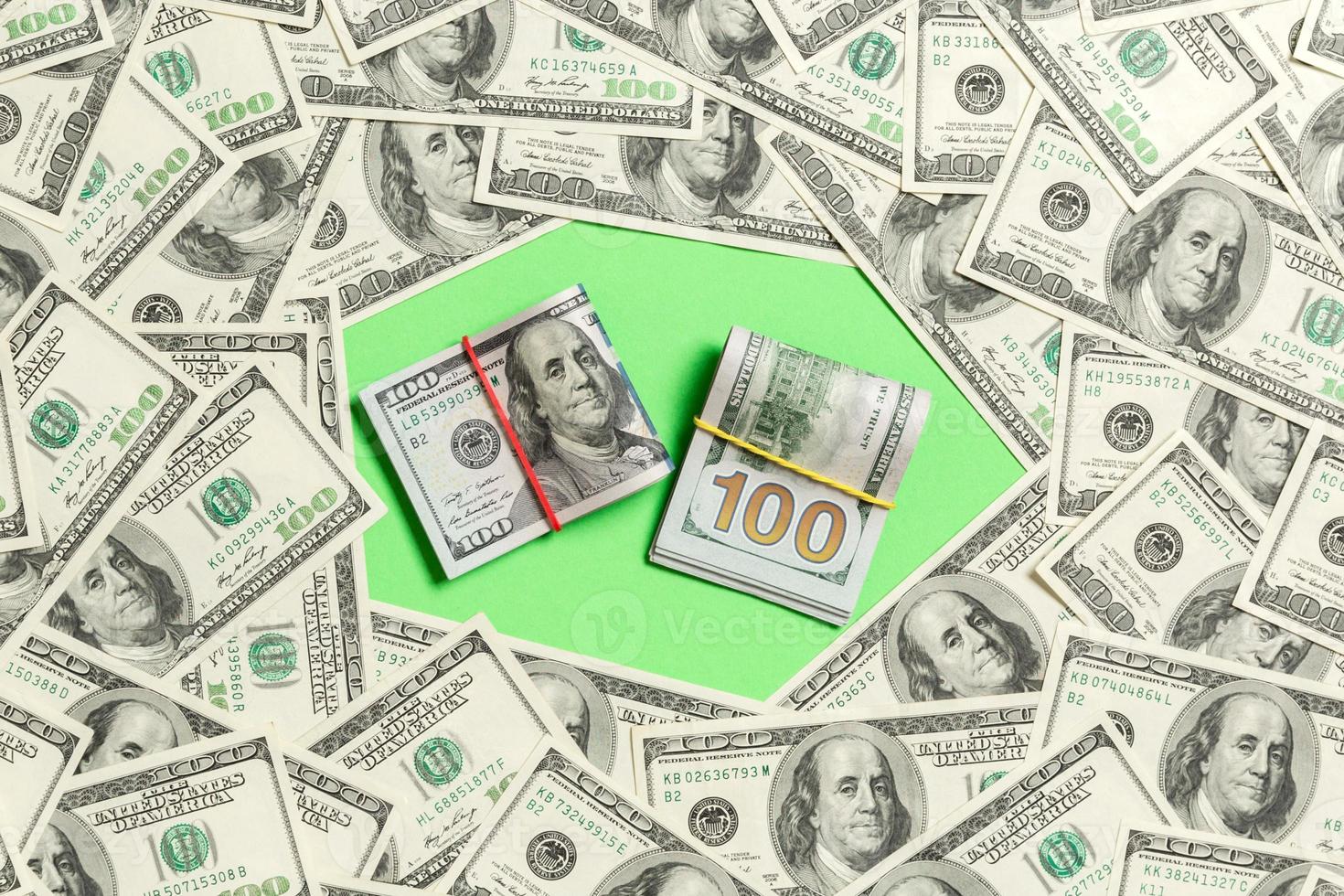 Frame of one hundred dollar bills with stack of money in the middle. Top view of business concept on green background with copy space photo