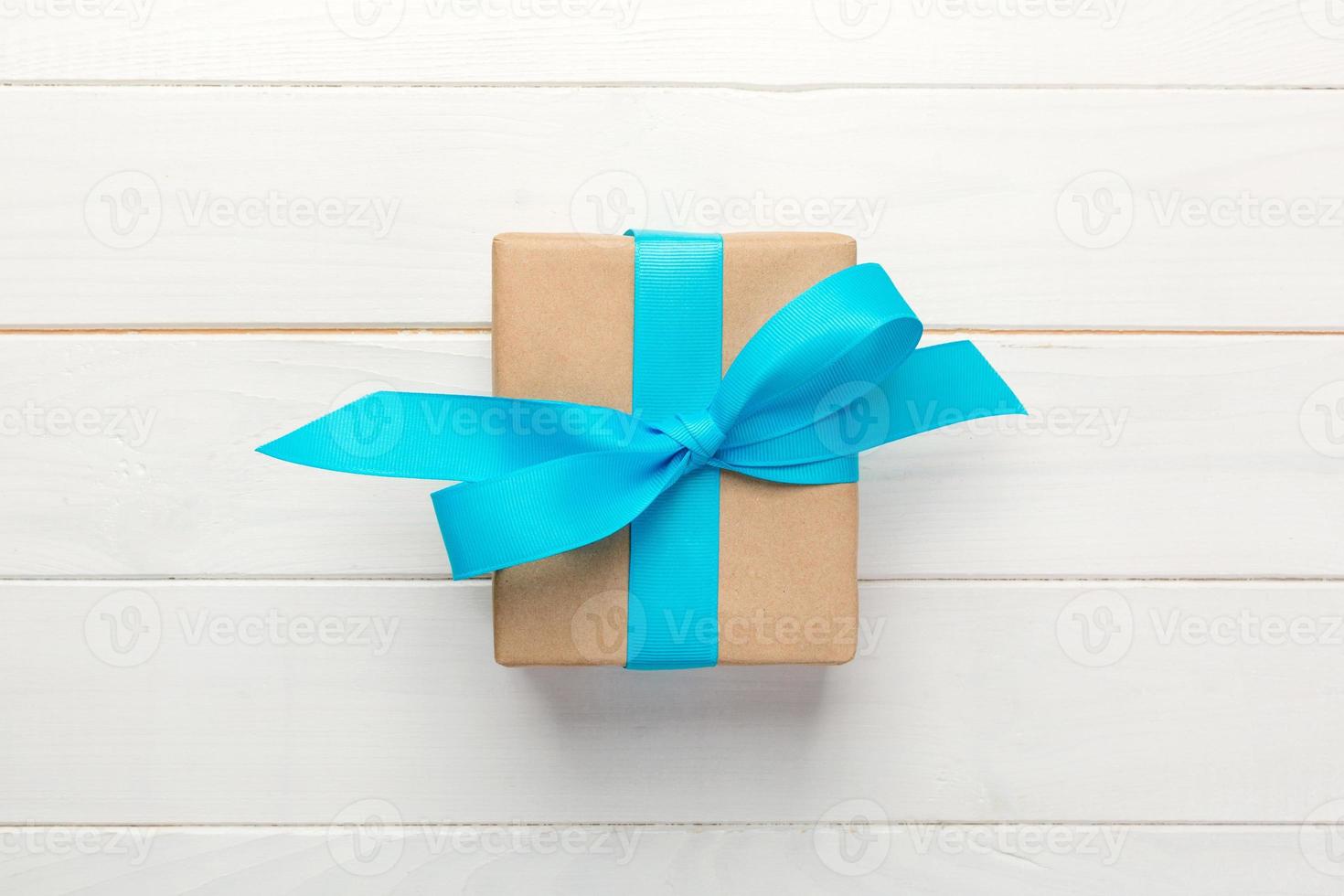 Gift box with blue bow over white wooden table with copy space. top view photo
