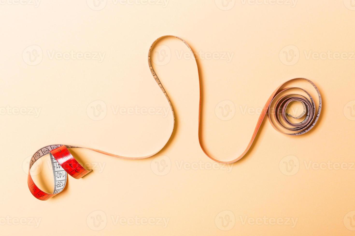 Creative idea of spiral tape measure on orange background. Sewing concept photo