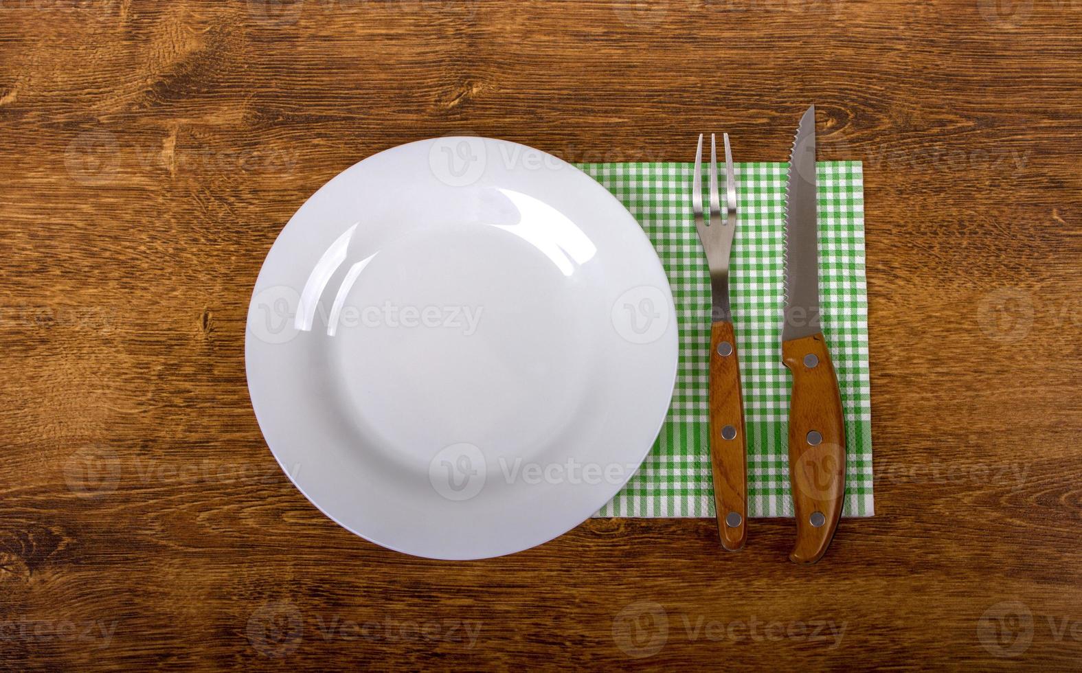 plato vacío, tenedor y cuchillo sobre fondo de madera. foto