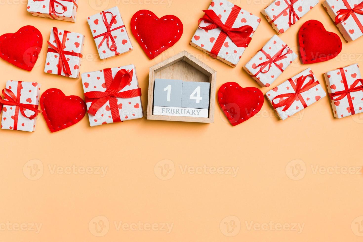Top view of gift boxes, wooden calendar and red textile hearts on colorful background. The fourteenth of february. St Valentine's day concept with copy space photo