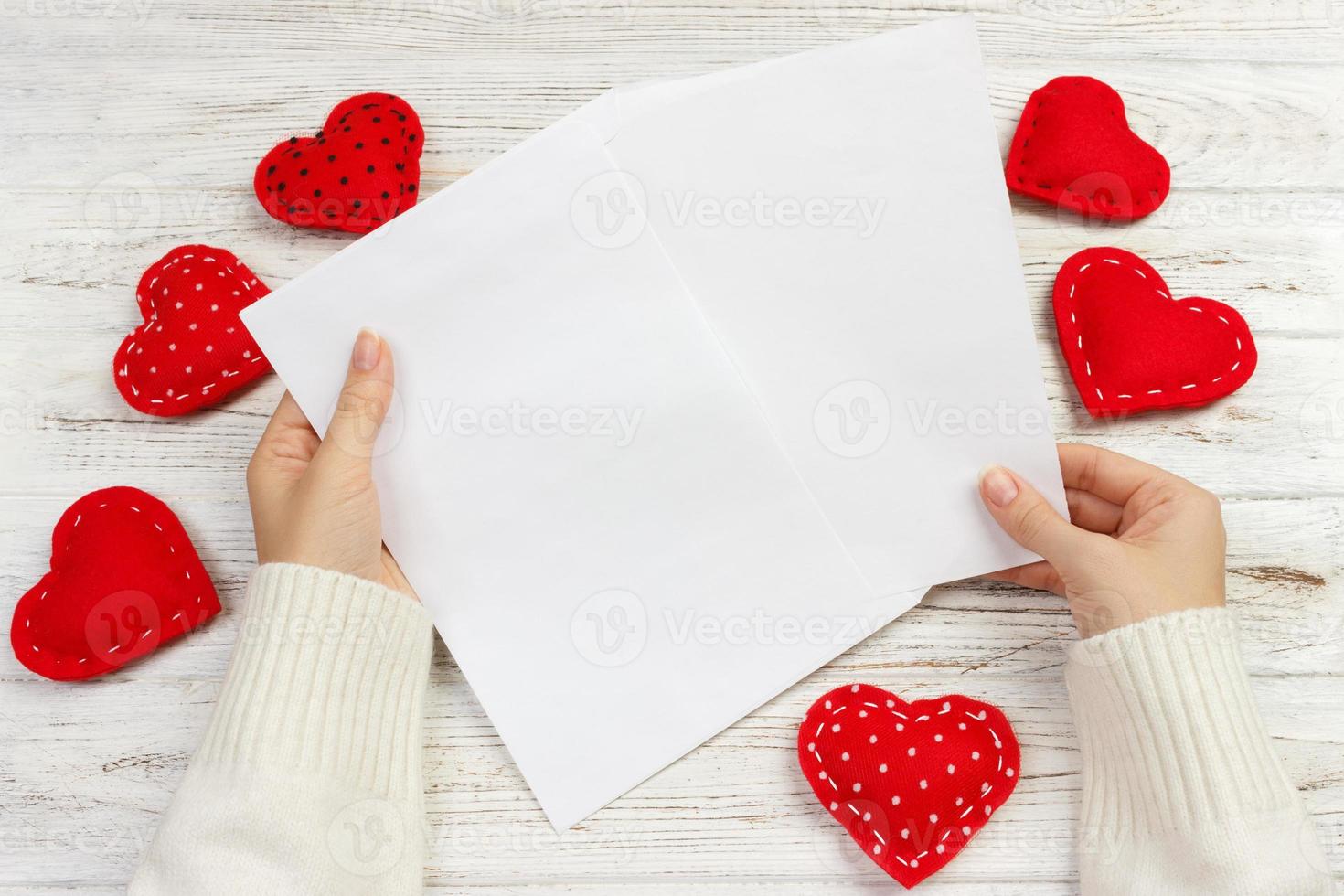 A female woman hand hold open a envelope and post card on the wood desk, top view photo