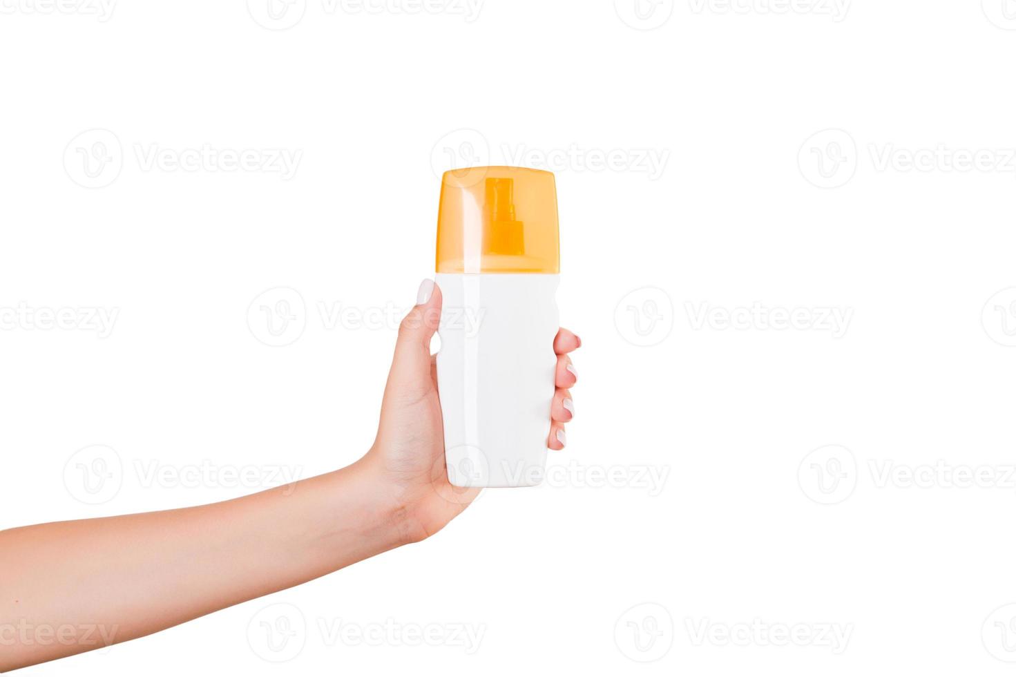 Female hand holding cream bottle of lotion isolated. Girl give cosmetic products on white background photo