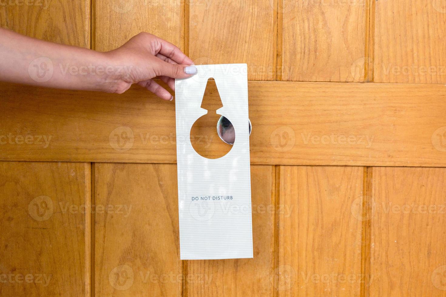 female hand hangs a sign on the door do not disturb in hotel photo