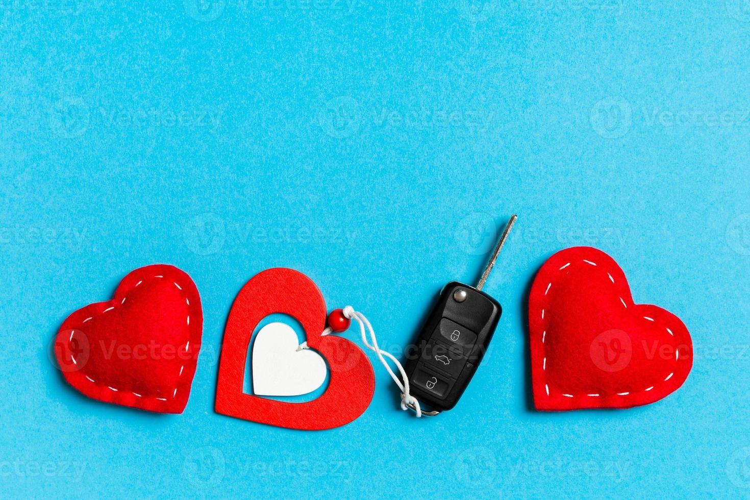 Top view of gift box, car key, wooden and textile heart on colorful background. Luxury present for Valentine's day photo