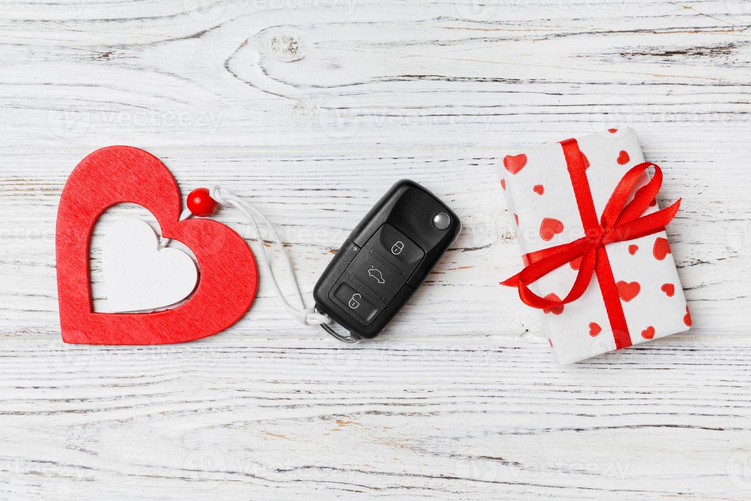 Top view of a present for Valentine's Day on wooden background. Close up of car key, gift box and heart. Surprise concept for a holiday photo
