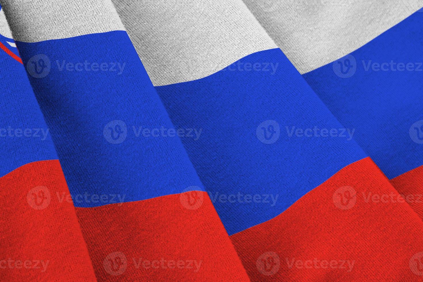 Slovenia flag with big folds waving close up under the studio light indoors. The official symbols and colors in banner photo