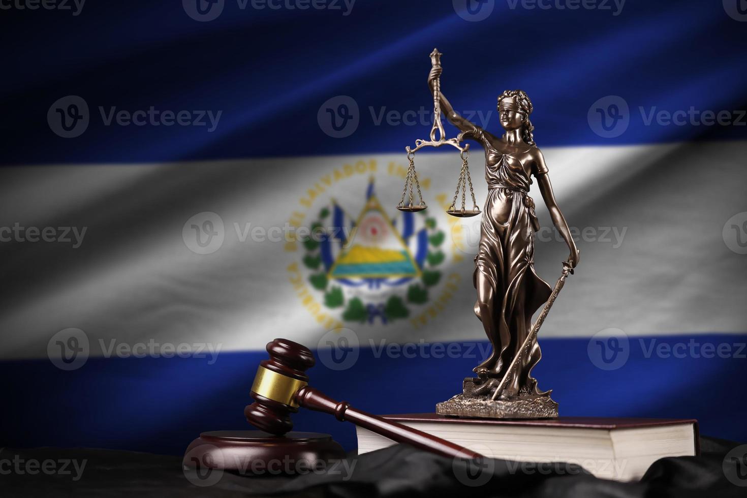 la bandera de el salvador con la estatua de la dama de la justicia, la constitución y el juez martillo sobre cortinas negras. concepto de juicio y culpa foto