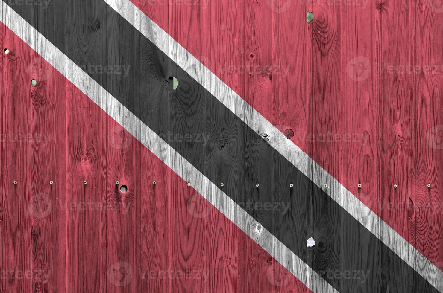 Trinidad and Tobago flag depicted in bright paint colors on old wooden wall. Textured banner on rough background photo