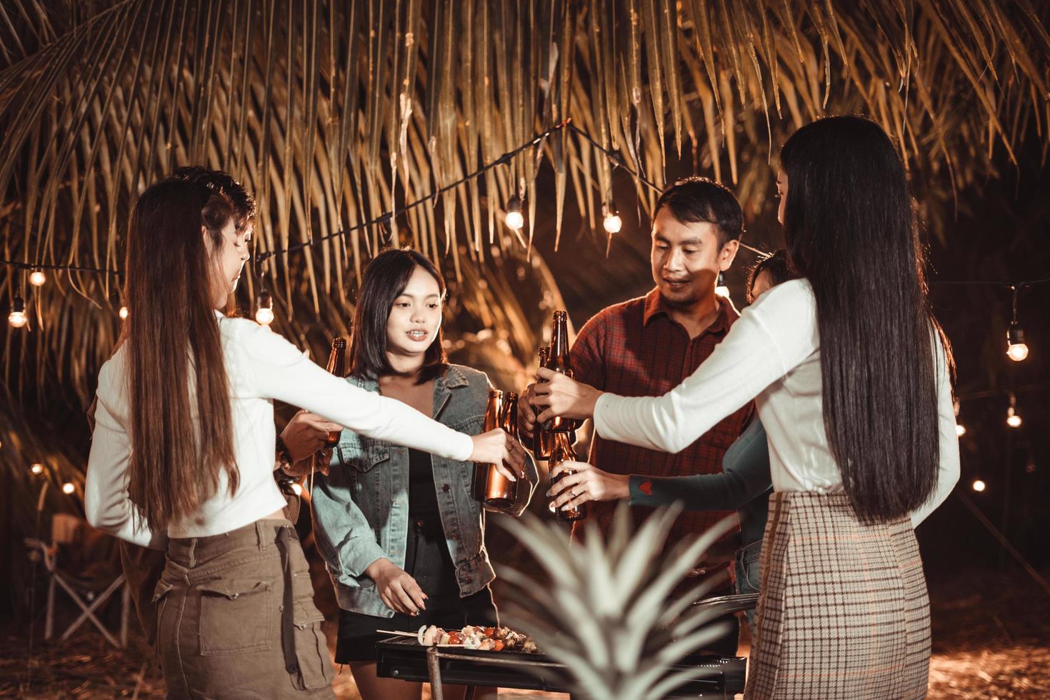 Group of Asian friends having fun barbecuing and drinking beer in the backyard. photo