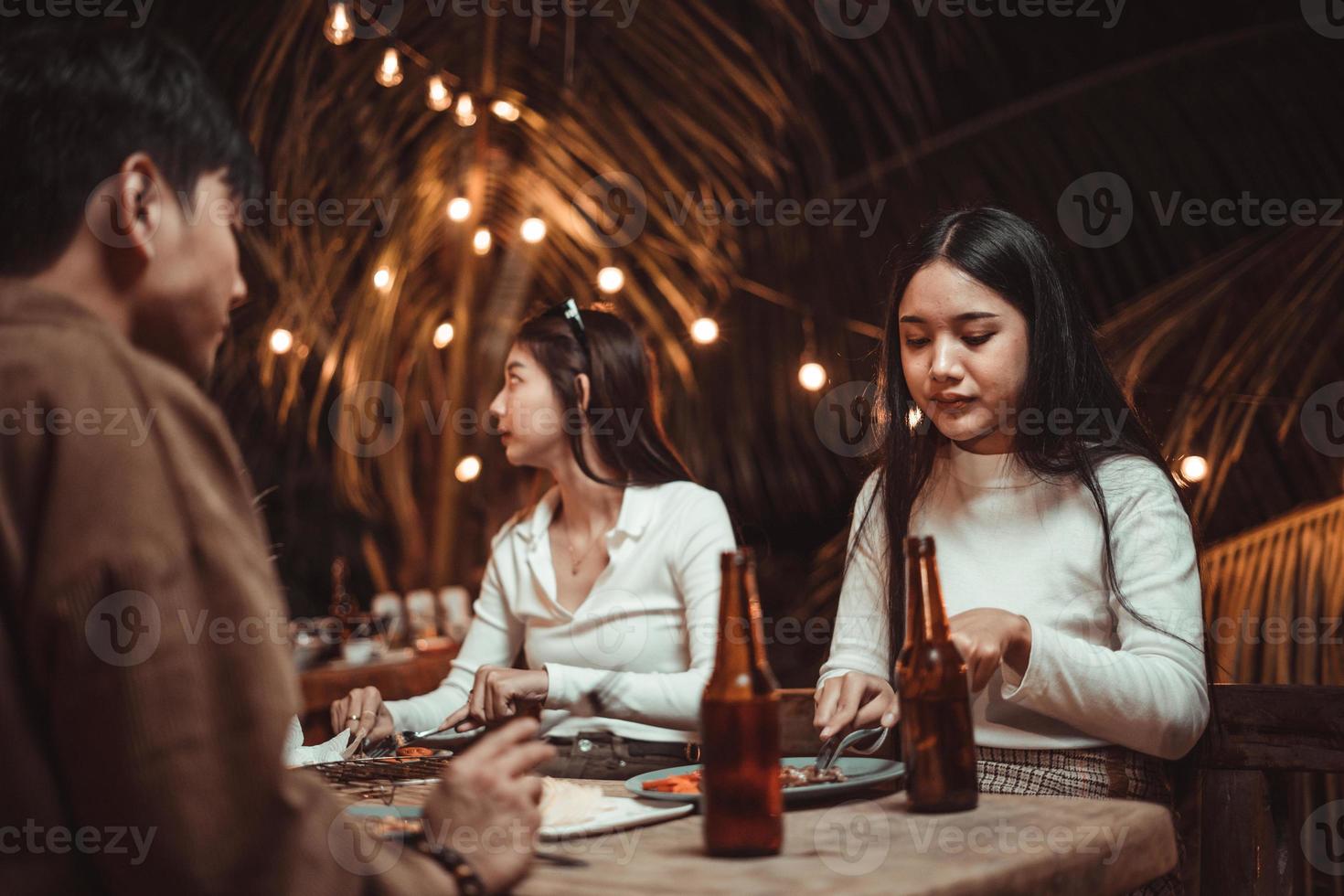 jóvenes comiendo bistec disfrutando con amigos en la fiesta foto