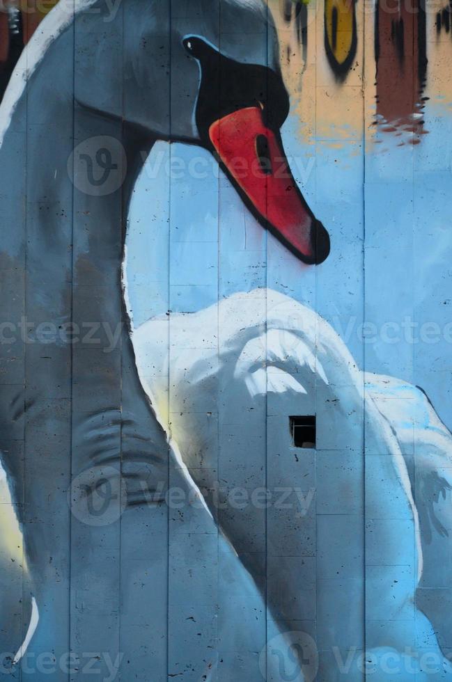 A fragment of detailed graffiti of a drawing made with aerosol paints on a wall of concrete tiles. Background image of street art with a huge white swan photo