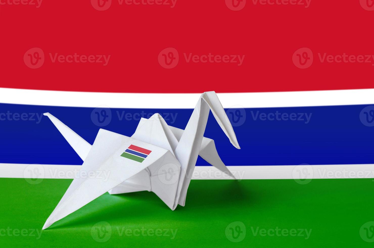 bandera de gambia representada en el ala de la grúa de origami de papel. concepto de artes hechas a mano foto