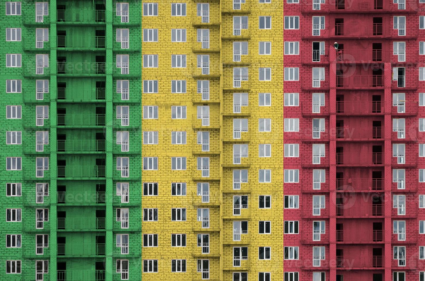 Mali flag depicted in paint colors on multi-storey residental building under construction. Textured banner on brick wall background photo