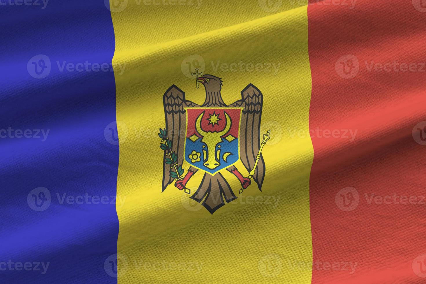 Moldova flag with big folds waving close up under the studio light indoors. The official symbols and colors in banner photo