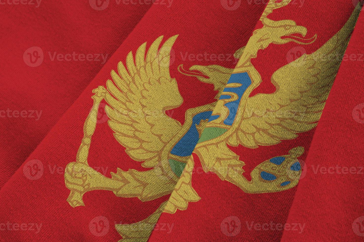 Montenegro flag with big folds waving close up under the studio light indoors. The official symbols and colors in banner photo