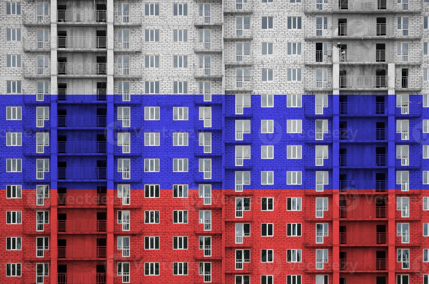 Russia flag depicted in paint colors on multi-storey residental building under construction. Textured banner on brick wall background photo