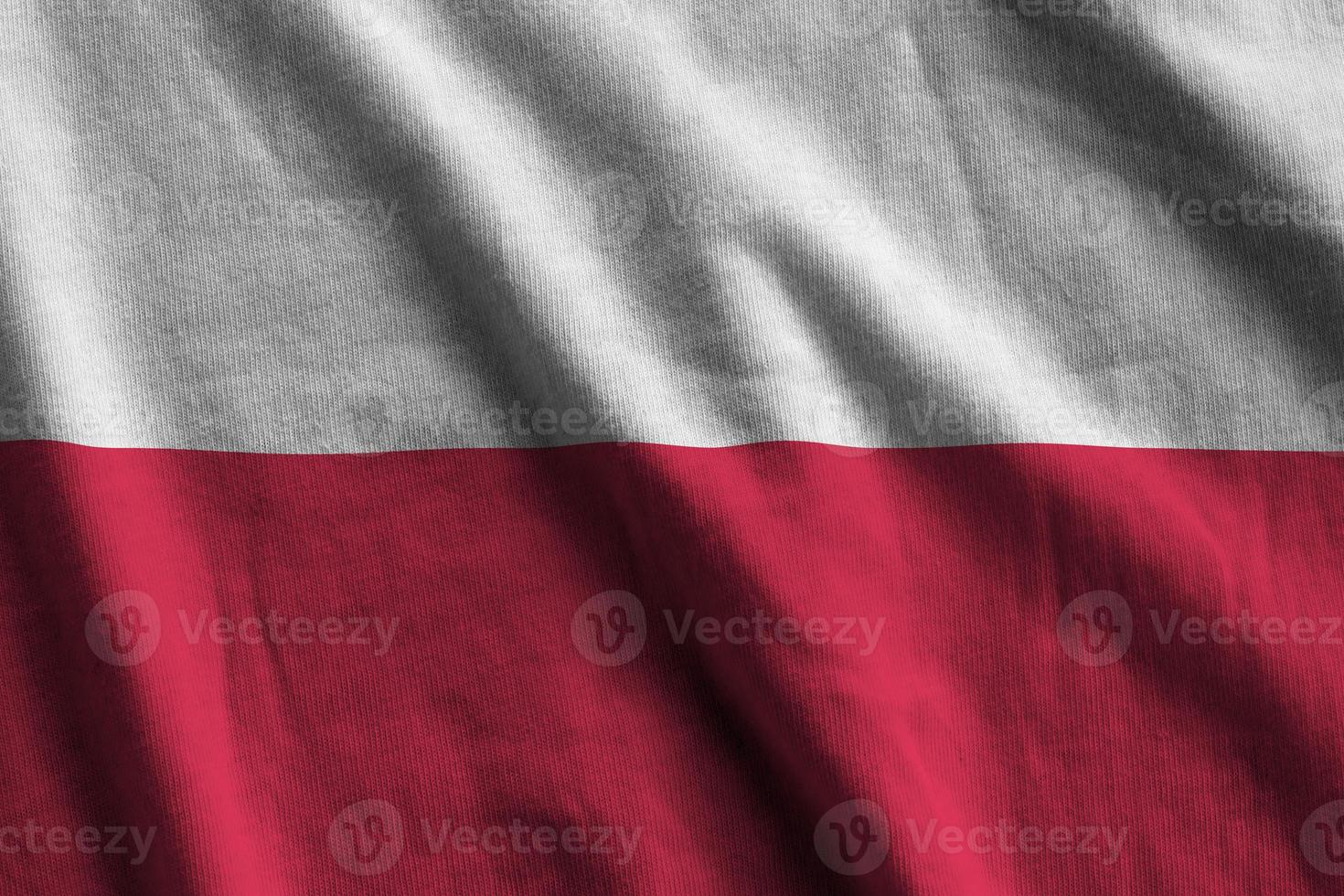 Poland flag with big folds waving close up under the studio light indoors. The official symbols and colors in banner photo