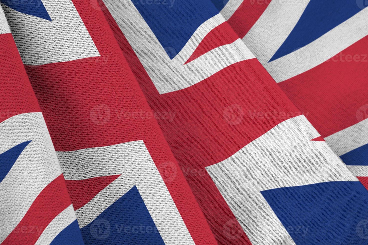 Great britain flag with big folds waving close up under the studio light indoors. The official symbols and colors in banner photo