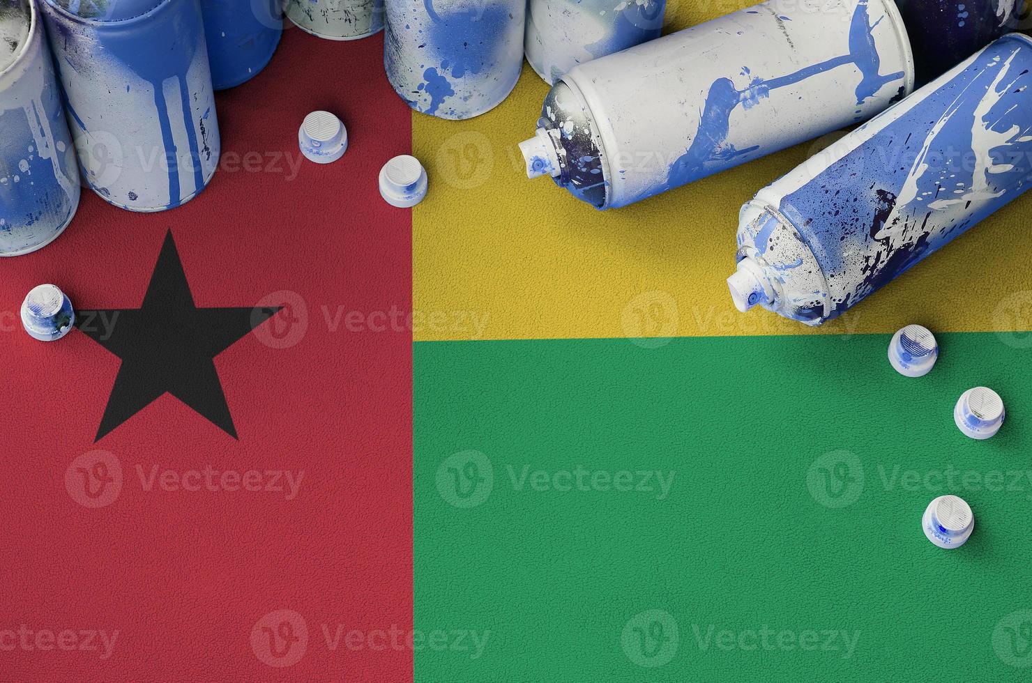 Guinea Bissau flag and few used aerosol spray cans for graffiti painting. Street art culture concept photo