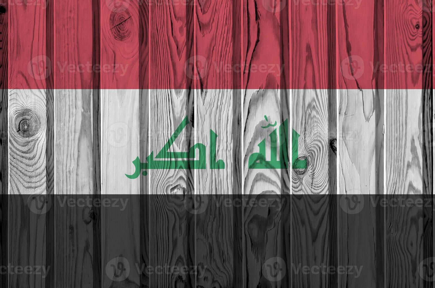 Iraq flag depicted in bright paint colors on old wooden wall. Textured banner on rough background photo