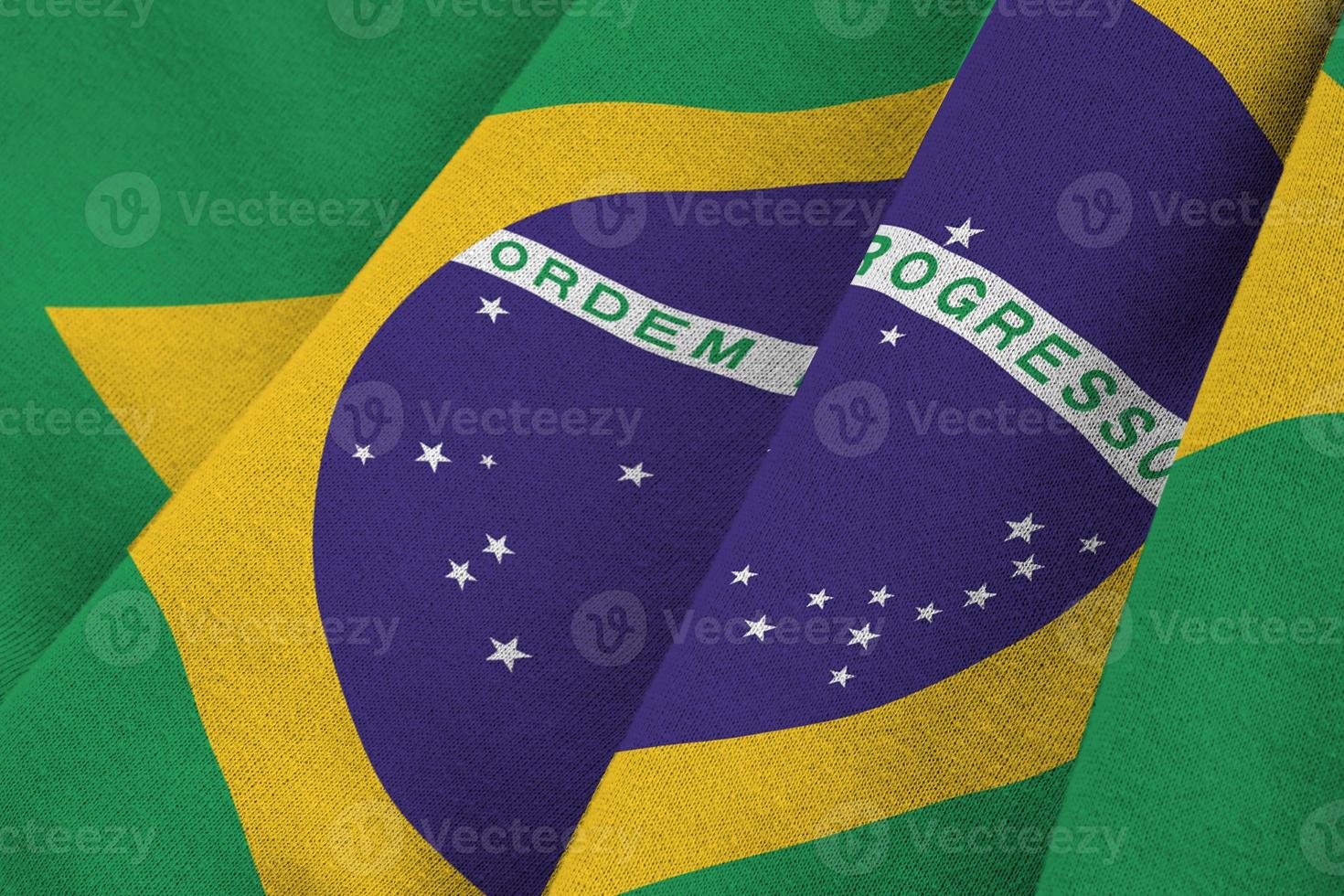 Brazil flag with big folds waving close up under the studio light indoors. The official symbols and colors in banner photo