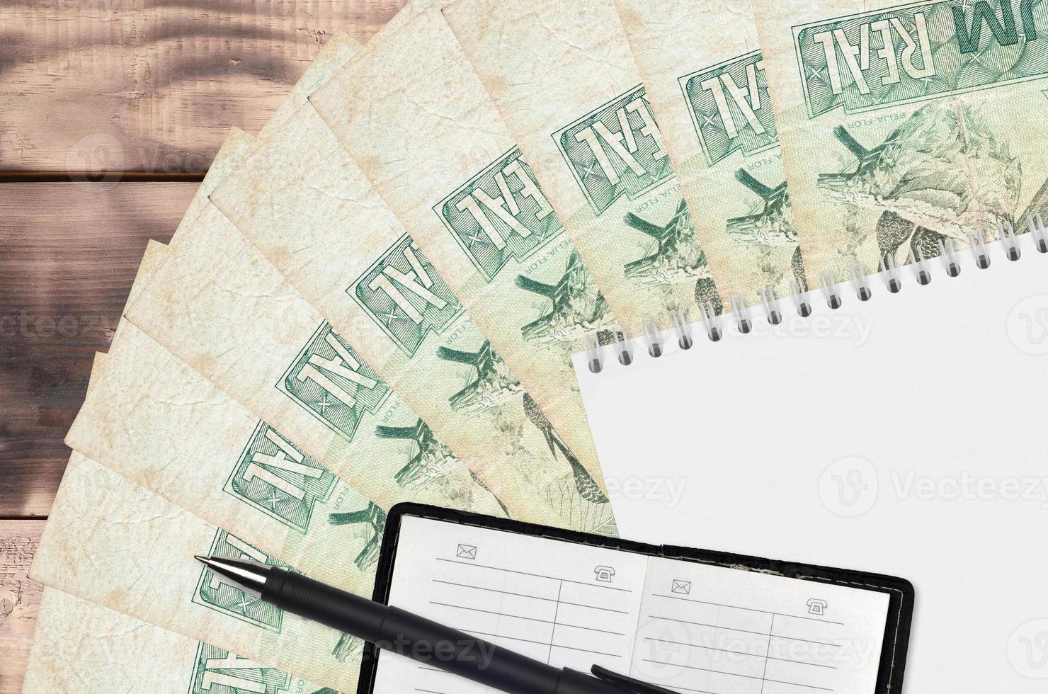 1 abanico de billetes reales brasileños y bloc de notas con libreta de contactos y bolígrafo negro. concepto de planificación financiera y estrategia empresarial foto