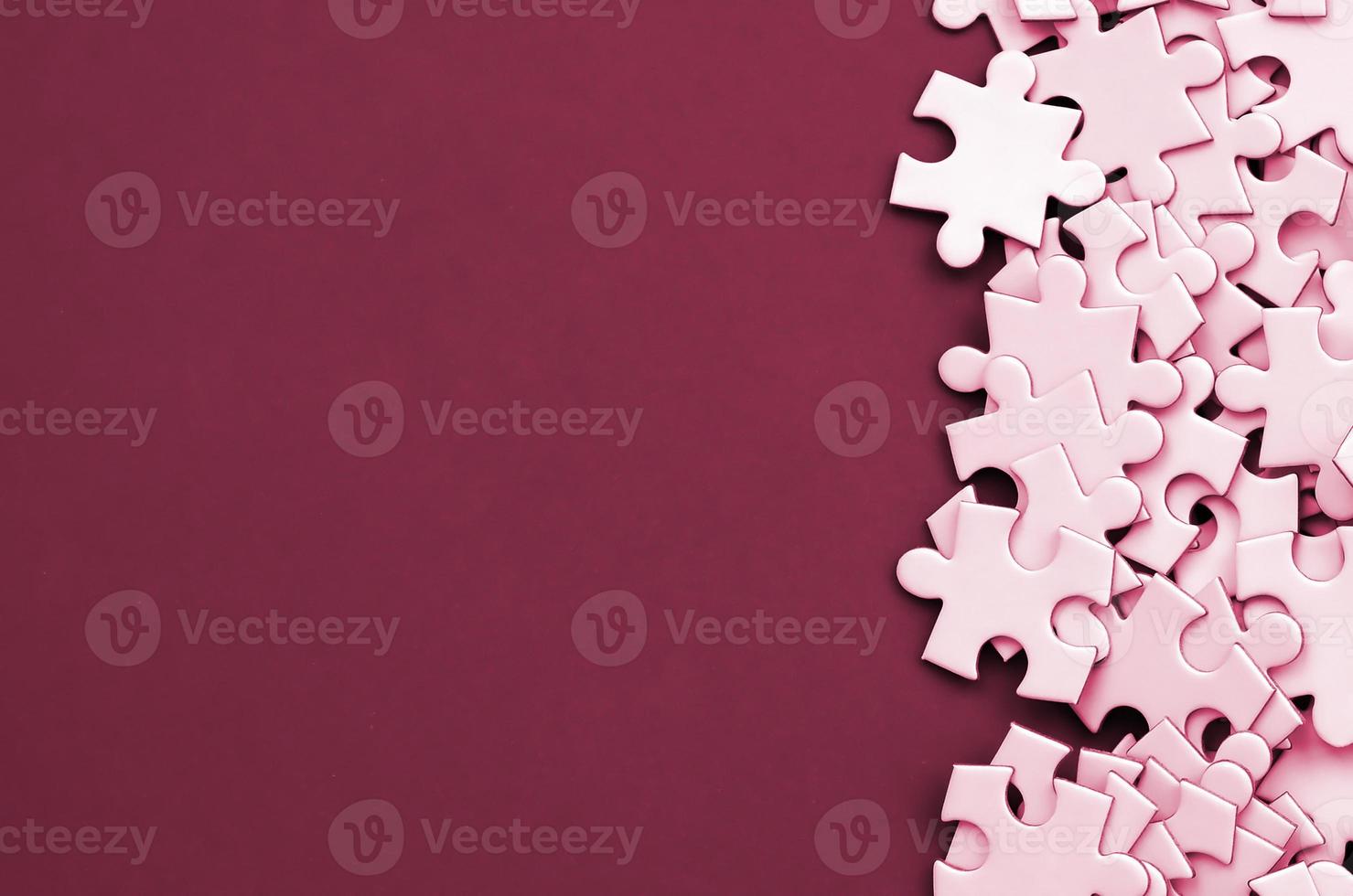 A pile of uncombed elements of a white jigsaw puzzle lies on the background of surface. Texture photo with copy space for text Image toned in Viva Magenta, color of the 2023 year