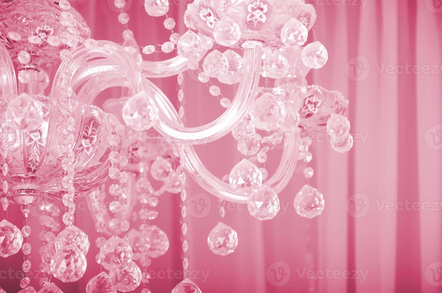 Close-up photo of the scenery on the old chandelier. Glass figures shine and reflect light with their faces Image toned in Viva Magenta, color of the year