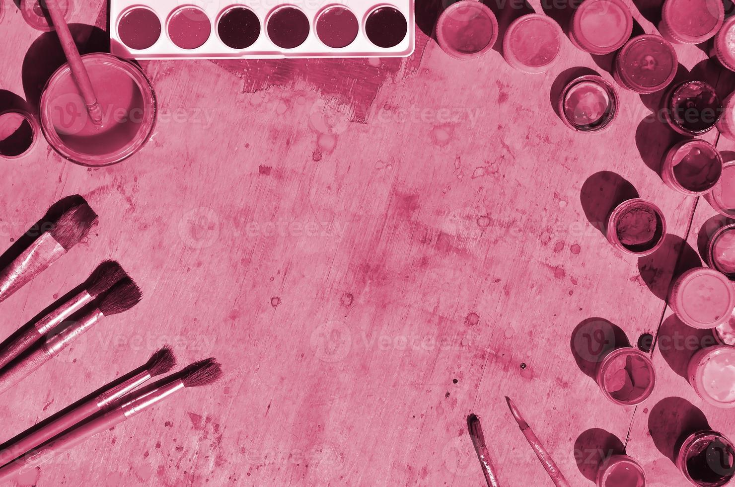 Still life with a lot of brushes and jars of watercolor and gouache paint Image toned in Viva Magenta, color of the 2023 year photo