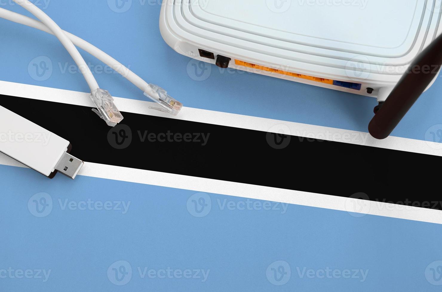 Botswana flag depicted on table with internet rj45 cable, wireless usb wifi adapter and router. Internet connection concept photo