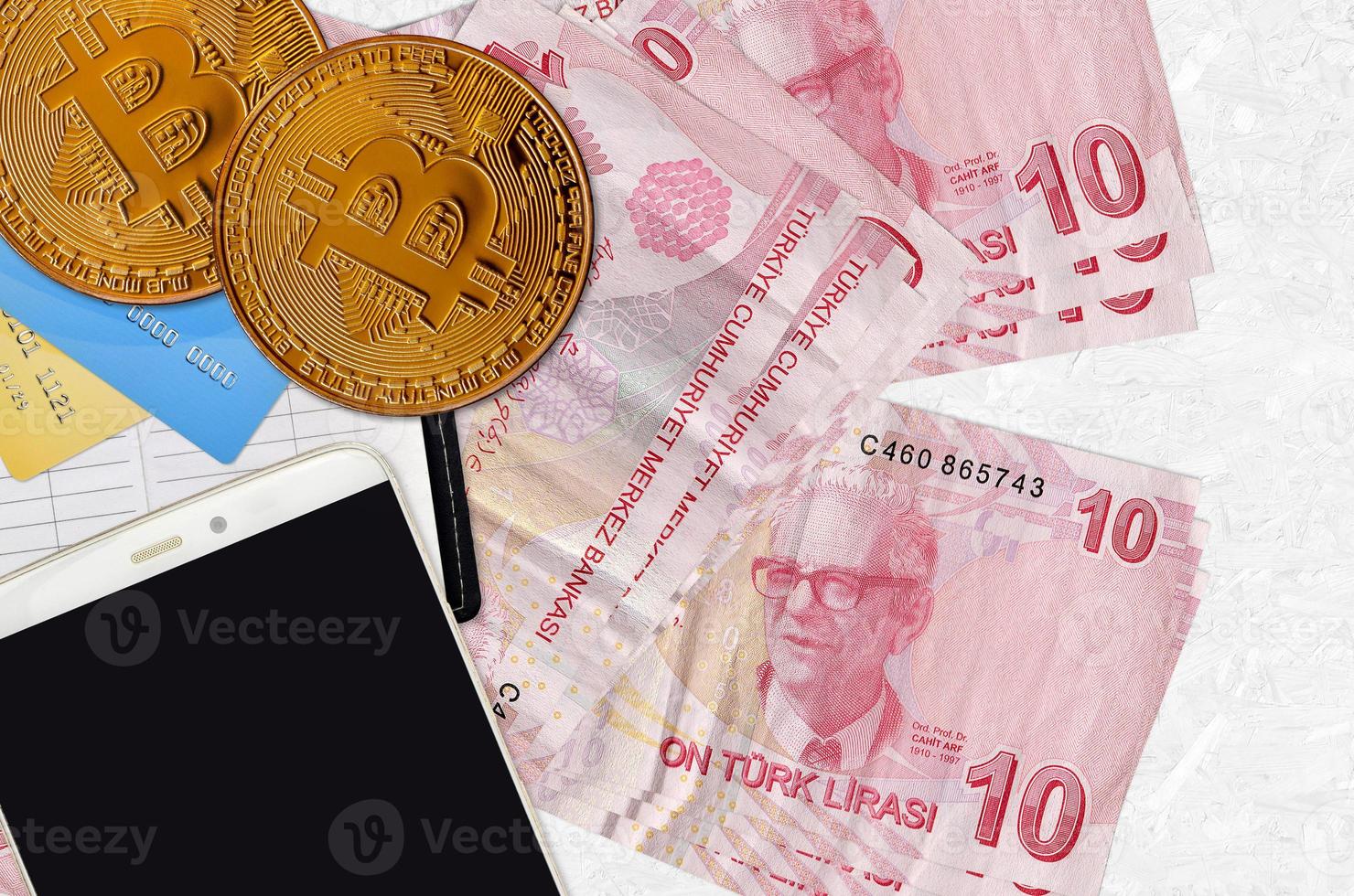 10 Turkish liras bills and golden bitcoins with smartphone and credit cards. Cryptocurrency investment concept. Crypto mining or trading photo