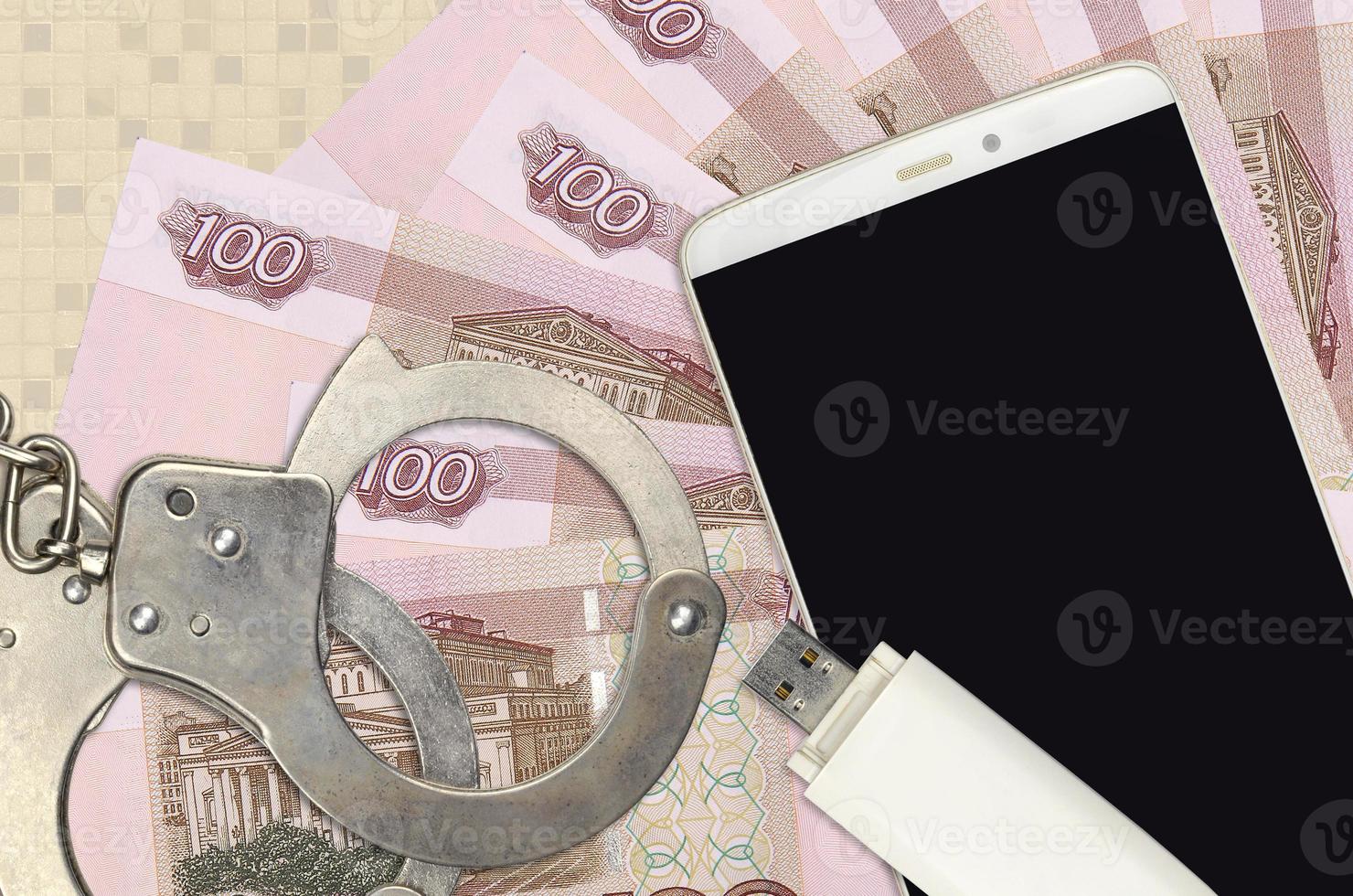 100 russian rubles bills and smartphone with police handcuffs. Concept of hackers phishing attacks, illegal scam or malware soft distribution photo