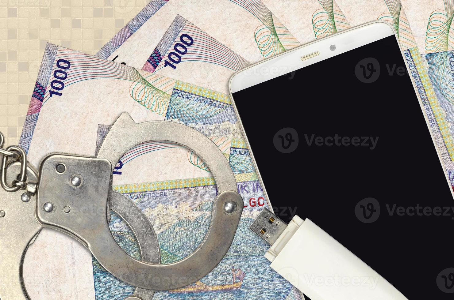 1000 Indonesian rupiah bills and smartphone with police handcuffs. Concept of hackers phishing attacks, illegal scam or malware soft distribution photo
