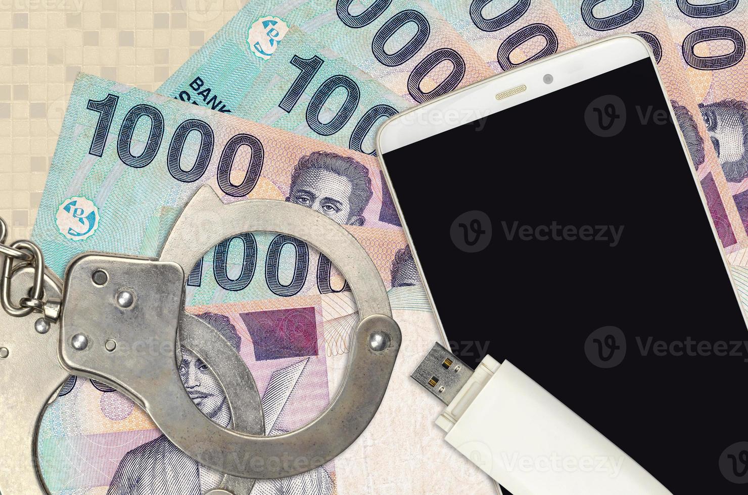 Billetes de 1000 rupias indonesias y teléfono inteligente con esposas policiales. concepto de ataques de phishing de piratas informáticos, estafa ilegal o distribución blanda de malware foto